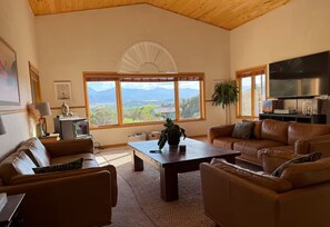 A spacious living room with leather sofas, a coffee table, and a large TV. - Highwater House - Arkansas River Basecamp #020886 (Salida)