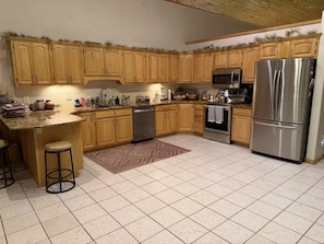 A kitchen with wooden cabinets, stainless steel appliances, a granite countertop, and a patterned rug. - Highwater House - Arkansas River Basecamp #020886 (Salida)