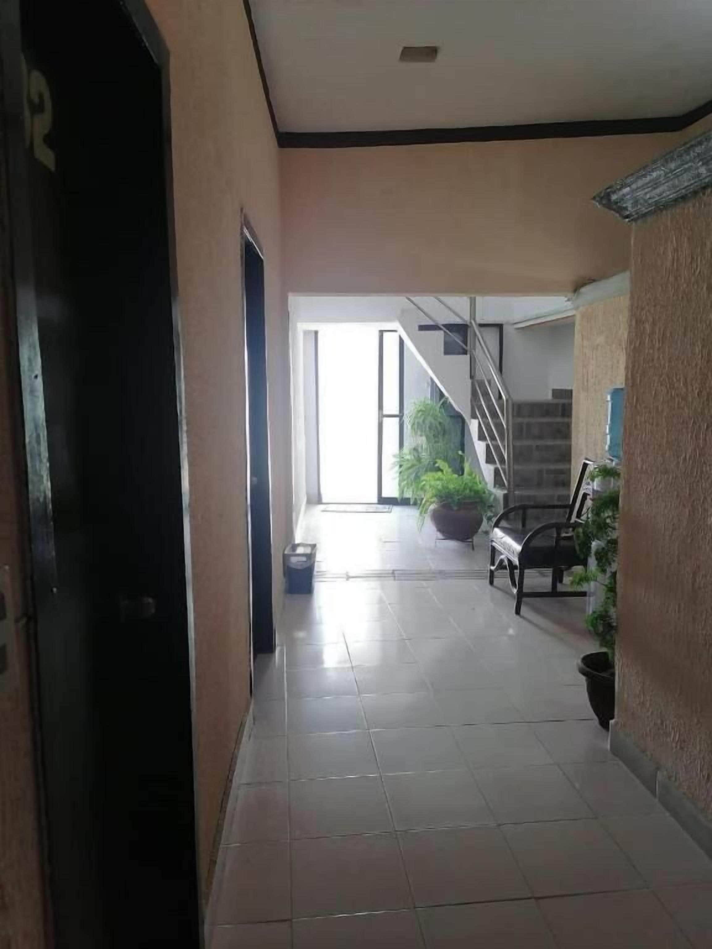 A hallway with a tiled floor, a staircase, and potted plants.