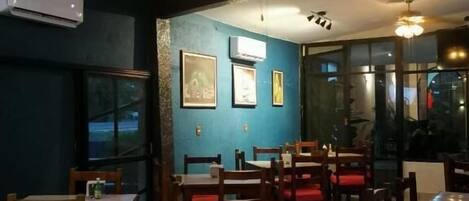 A restaurant interior with wooden tables and chairs, ceiling fans, and framed pictures on the walls.