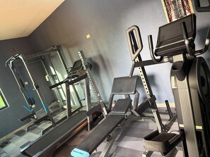 Une salle de sport équipée de tapis de course, d’appareils de musculation et d’un banc.
