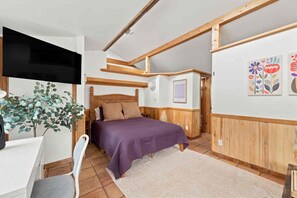 A bedroom with a bed, a desk, a chair, a plant, and wooden paneling. - Garden Loft close to CU, trails and Pearl Street (Boulder)