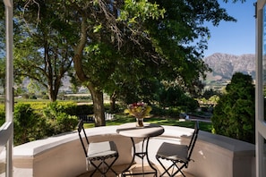 Eine Terrasse im Freien mit zwei Stühlen und einem Tisch, mit Blick auf eine gebirgige Landschaft.