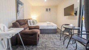 Une chambre d’hôtel de taille réduite, comprenant un lit, un canapé, une petite table et une chaise.