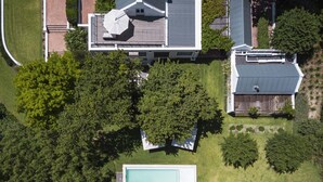 Vista aérea de uma propriedade residencial com piscina, varanda coberta e quintal cercado.