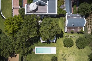 Luftaufnahme eines Wohnhauses mit Schwimmbad, überdachter Terrasse und umzäunter Garten.