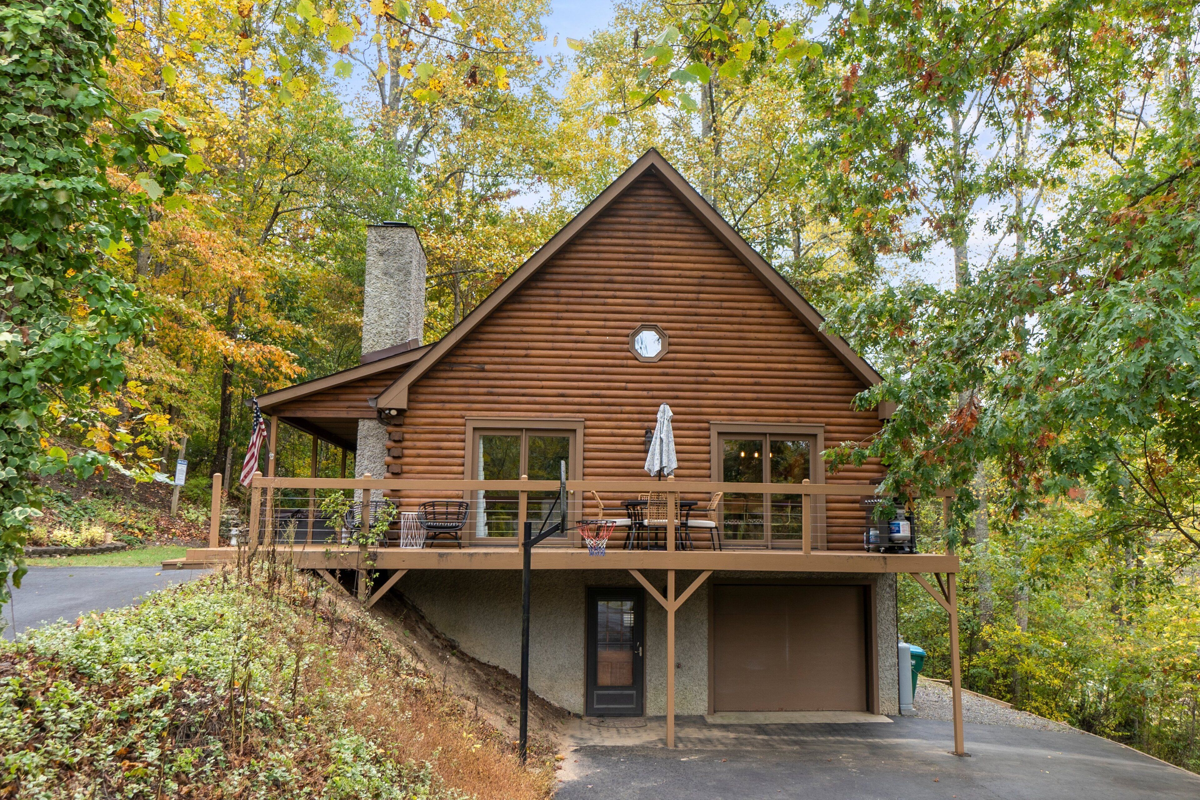 A log cabin with a balcony, a garage, and a chimney.