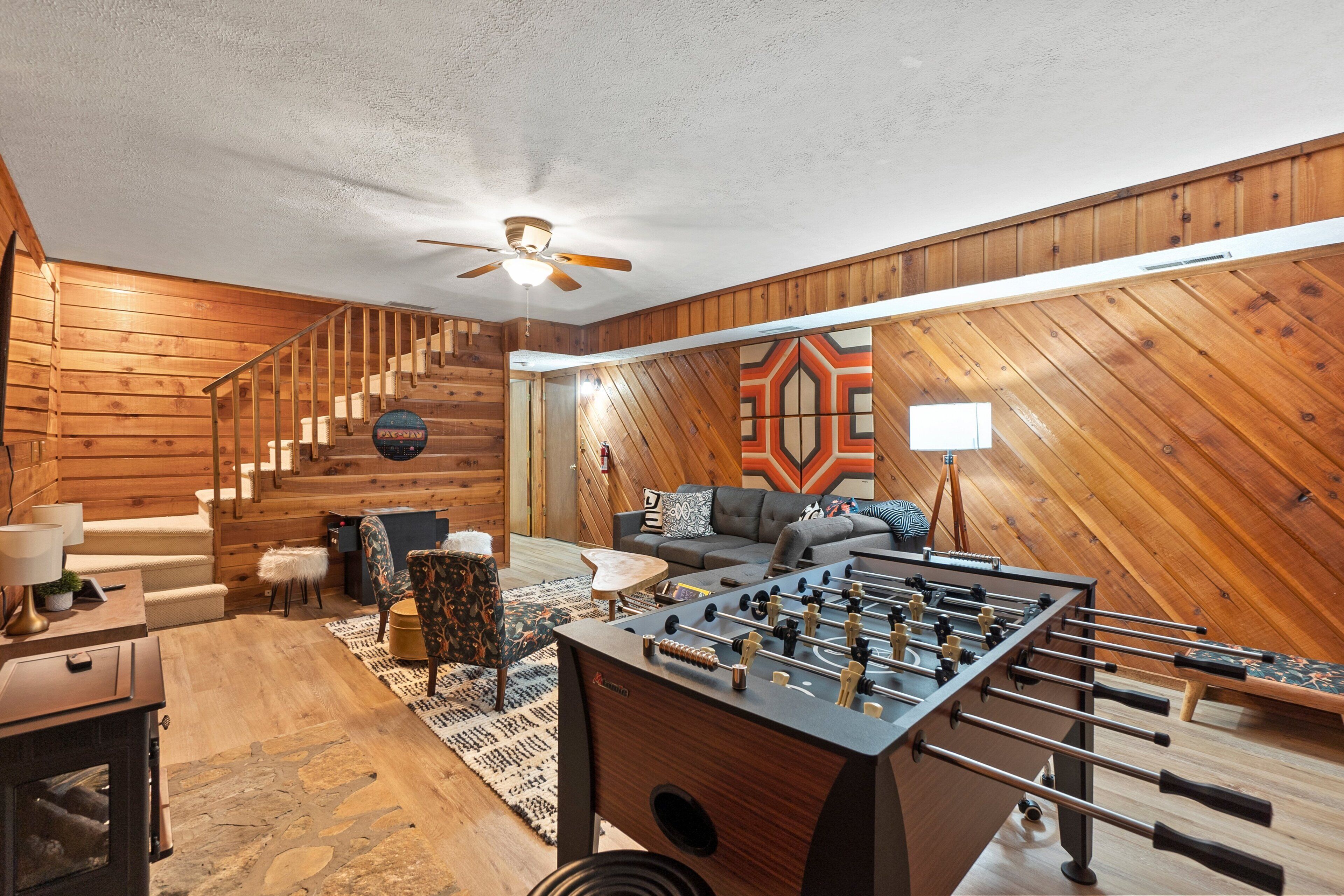 Een gezellige kamer met houten details, een bank, een bijzettafeltje en een tafelvoetbaltafel.
