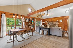 Ein gemütliches Blockhaus-Interieur mit Essbereich, Küche und einem Kamin aus Stein.