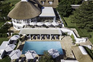 Ein Resort mit Schwimmbad, Liegestühlen, Sonnenschirmen und einem markanten Gebäude mit abgerundetem Dach.