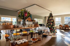 A spacious room with a large dining table set for a meal, a Christmas tree, and a window with a view. - Elegant Shiraz Room with Vineyard & Mountain Views 1037 (Western Cape)