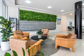 Eine moderne Lobby mit Ledersofas, einem runden schwarzen Tisch und einer vertikalen grünen Wandbegrünung.