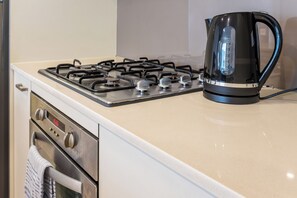 Une cuisine équipée d’une cuisinière à gaz, d’une bouilloire et d’un four.