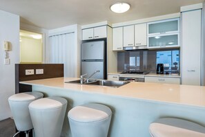 A modern kitchen with a central island, stainless steel appliances, and bar stools. - Prime Loc River Glimpse 2BR Walk to CBD w/Parking (Brisbane City)