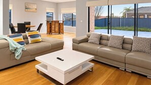 A spacious living room with a sofa set, a coffee table, and a dining area with chairs and a table.