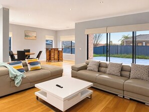 A spacious living room with a sofa set, a coffee table, and a dining area with chairs and a table.