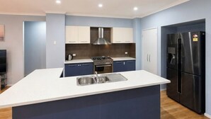 A modern kitchen with a central island, built-in appliances, and a flat-screen TV.