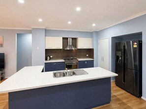 A modern kitchen with a central island, built-in appliances, and a flat-screen TV.
