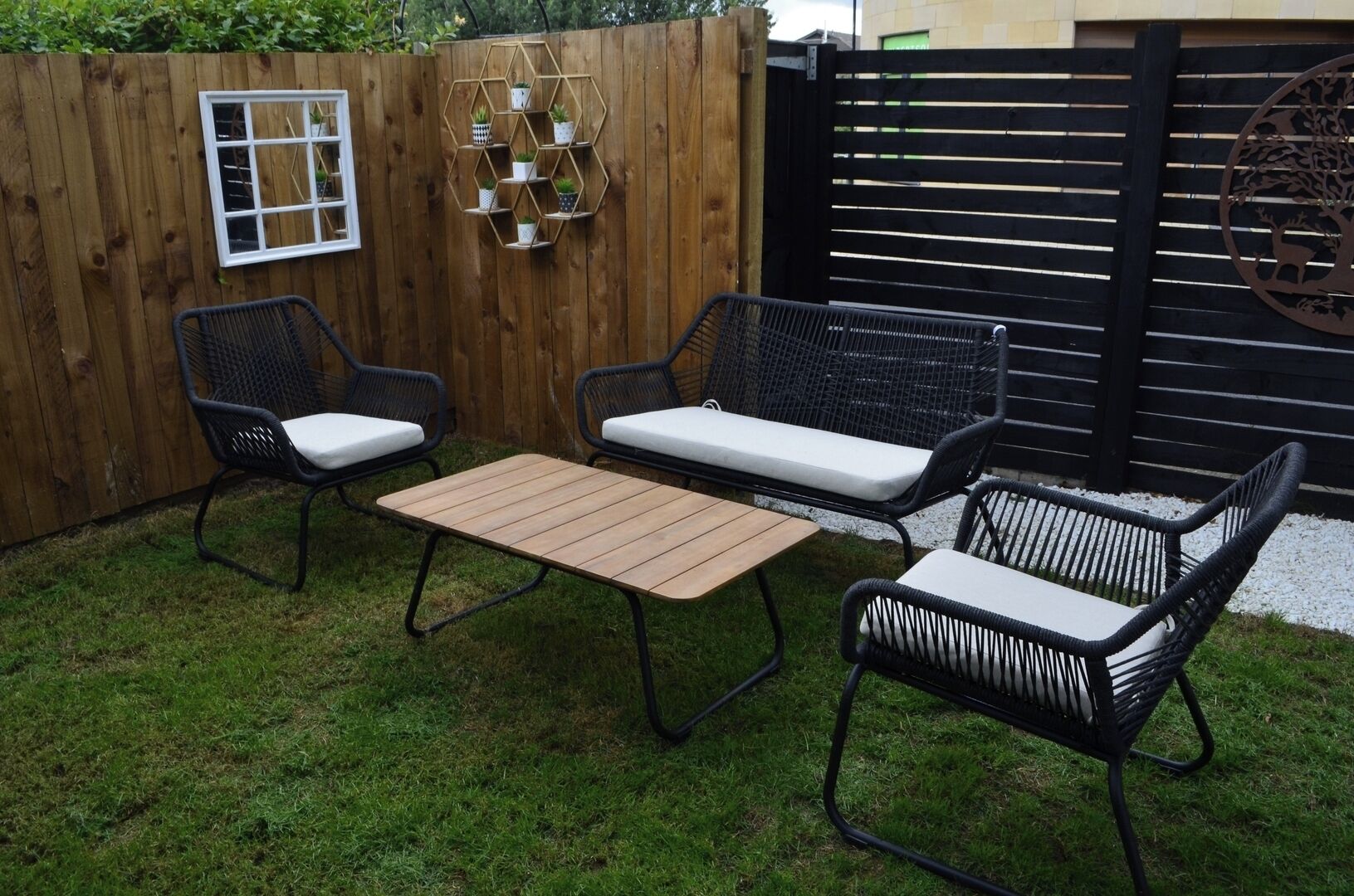 A patio with a wooden table and four wicker chairs with cushions.