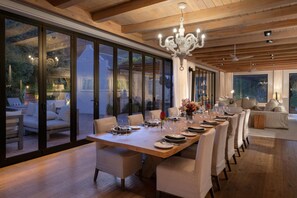 A dining area with a long table set for a meal, large windows, and a chandelier. - Chardonnay Room 2 Light Filled Elegant En Suite 1045 (Western Cape)