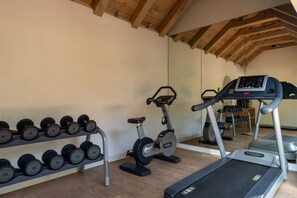 Ein Fitnessraum mit Laufbändern, Crosstrainern und einer Hantelbank.