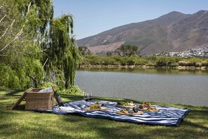 A picnic setup by a lake with a mountain backdrop. - Chardonnay Room 2 Light Filled Elegant En Suite 1045 (Western Cape)