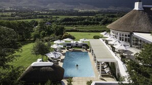 Un resort con piscina, lettini e vista sulle montagne.