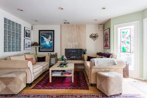 A living room with two sofas, a coffee table, a fireplace, and a large window with a stained glass design. - Mar Vista One Bedroom House - Great Location and Lots of Charm (Los Angeles)