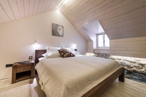 A bedroom with a sloped ceiling, a bed with a patterned bedspread, a nightstand, and a painting on the wall. - Villa Tihomira - Private villa with pool, Dalmatia (Zaton)