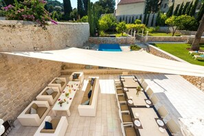 Eine sonnendurchflutete Terrasse im Freien mit Steinmauern, einem Swimmingpool und Sitzgelegenheiten.