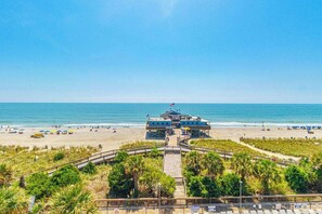 A beachside building with a flag, a boardwalk leading to it, and a clear view of the ocean. - Luxurious Coastal Oceanfront Suite! Yachtsman 601 (Myrtle Beach)