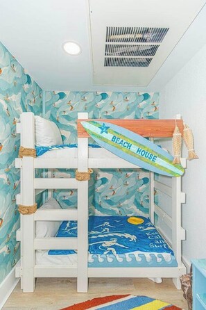 A bunk bed with a surfboard decoration and a beach-themed wall. - Luxurious Coastal Oceanfront Suite! Yachtsman 601 (Myrtle Beach)