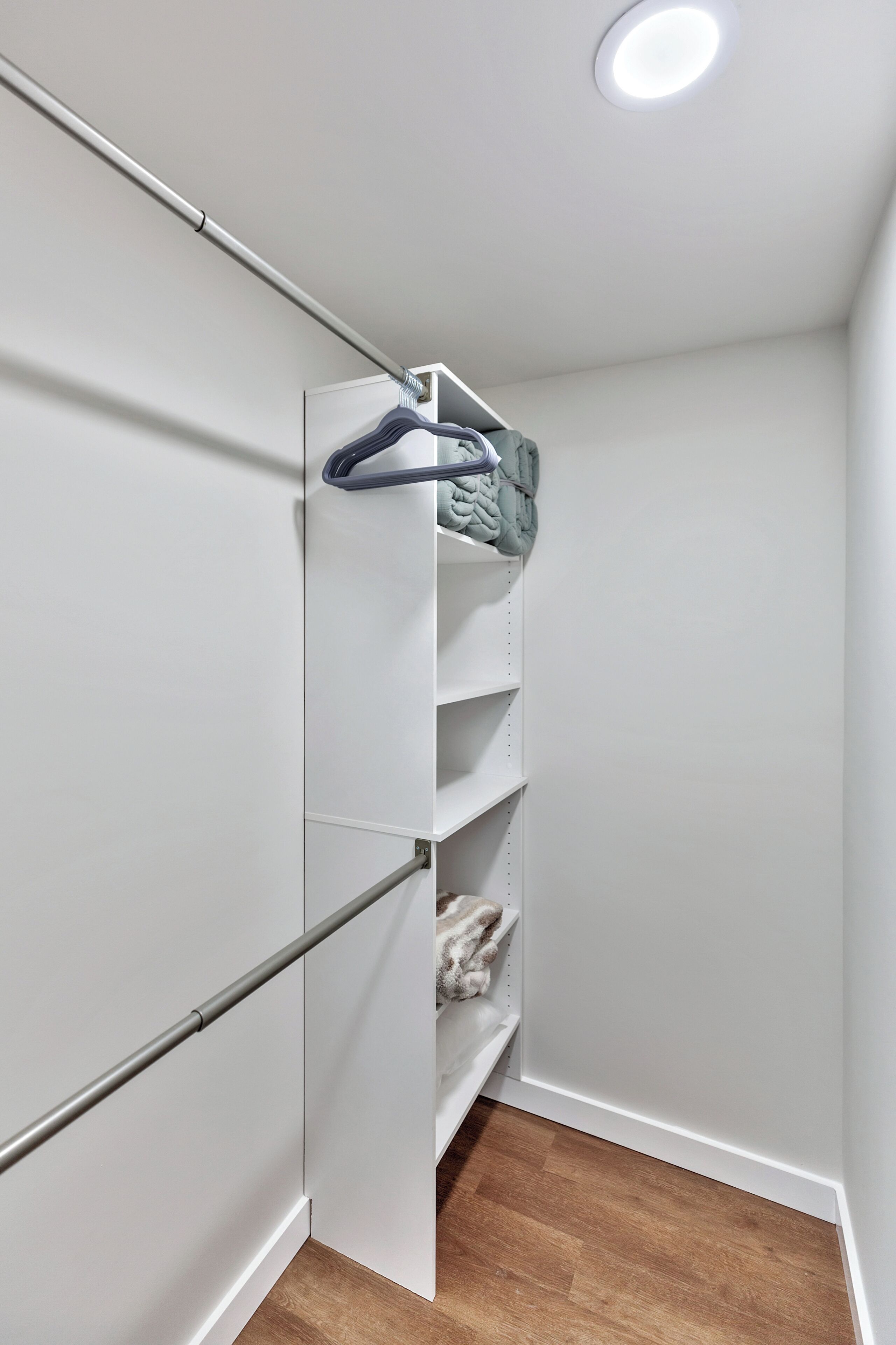 A walk-in closet with a metal rod rack, shelves, and a hanging rod for clothes.