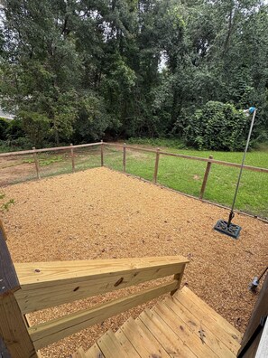 Eine Holzterrasse mit einem Metallzaun, umgeben von einem bewaldeten Gebiet.