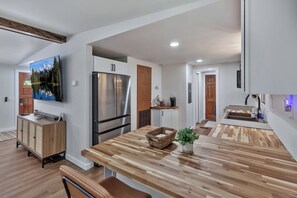 A modern kitchen with a wooden countertop, stainless steel appliances, and a flat-screen TV mounted on the wall. - 25 minutes from Clemson, newly remodeled home! (Seneca)