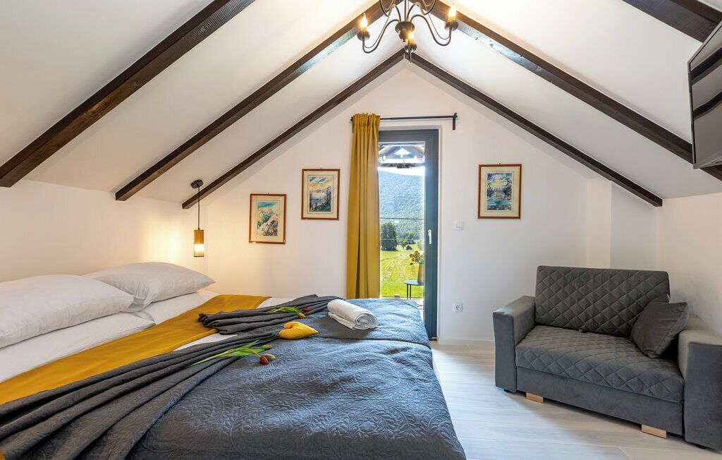 A bedroom with a bed, a sofa, and a window with curtains.