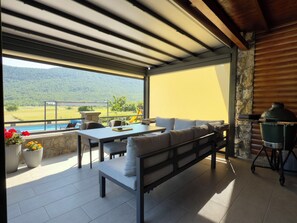 An outdoor patio with a table, chairs, a sofa, and a barbecue grill. - Holiday home with pool, sauna and jacuzzi overlooking Velebit (Gospić)