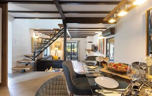 Ein modernes Interieur mit Essbereich, einer Treppe und Blick ins Freie.