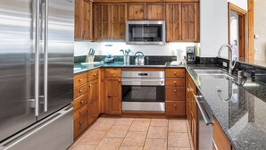 Een keuken met houten kastjes, roestvrijstalen apparatuur, een magnetron en een spoelbak.