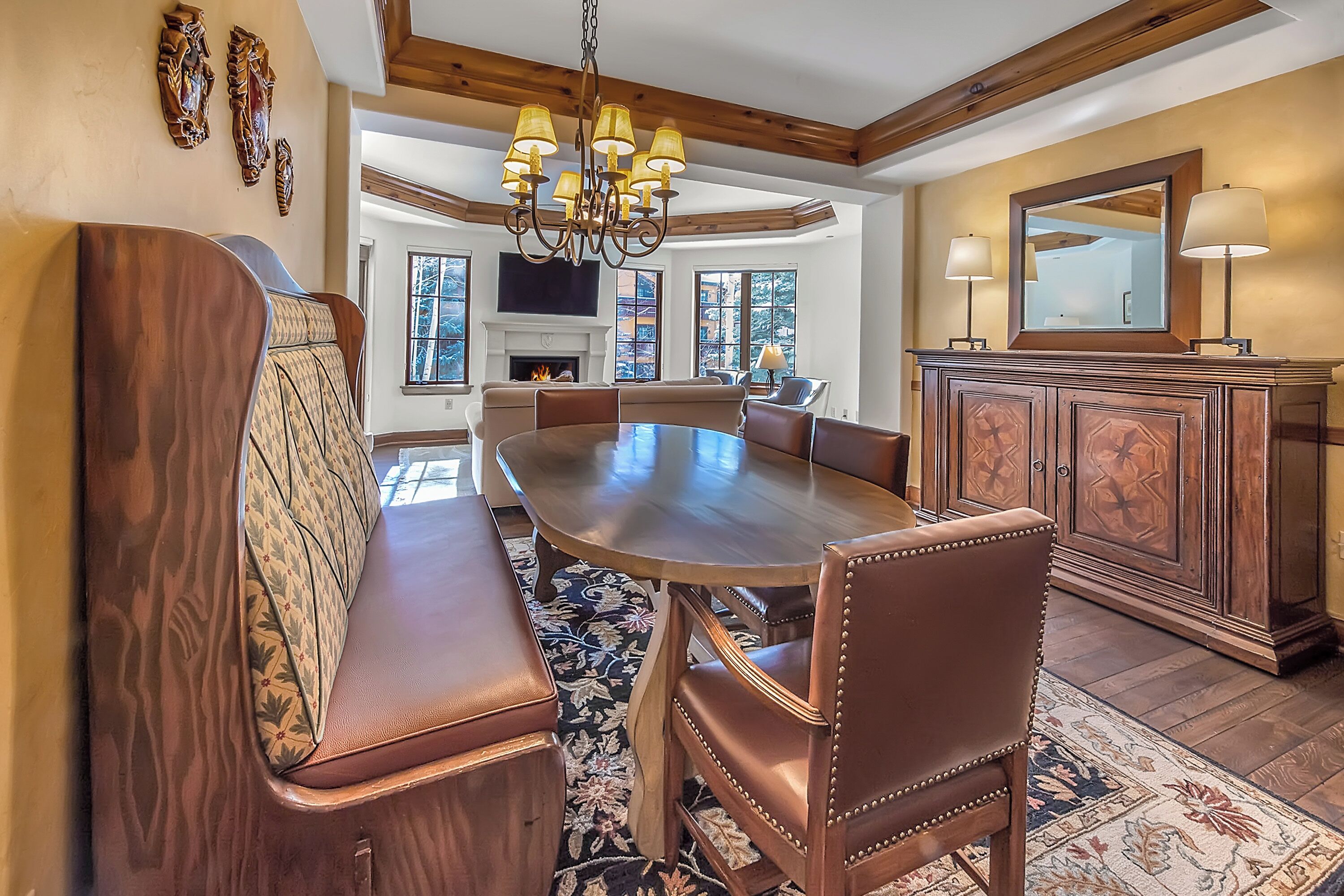 A dining area with a large wooden table, leather seating, and a chandelier.