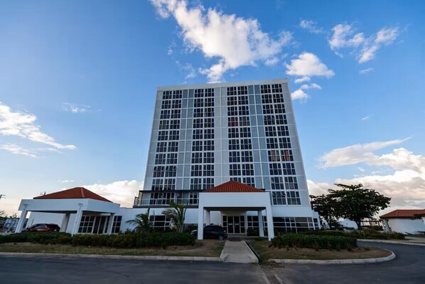 A multi-story building with a central entrance and a parking area in front. - Modern 2BR 2BA Oasis in Portmore • Smart TV • AC • Free Parking (Portmore)