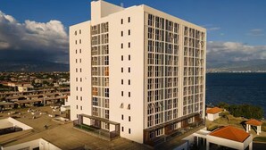 Un edificio moderno de varios pisos con techo plano, grandes ventanales y vista al mar.