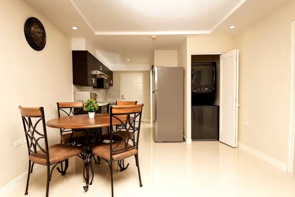 Una cocina moderna con comedor, que incluye una mesa con sillas, un refrigerador y un microondas.