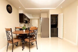 A modern kitchen with a dining area, including a table with chairs, a refrigerator, and a microwave. - Modern 2BR 2BA Oasis in Portmore • Smart TV • AC • Free Parking (Portmore)