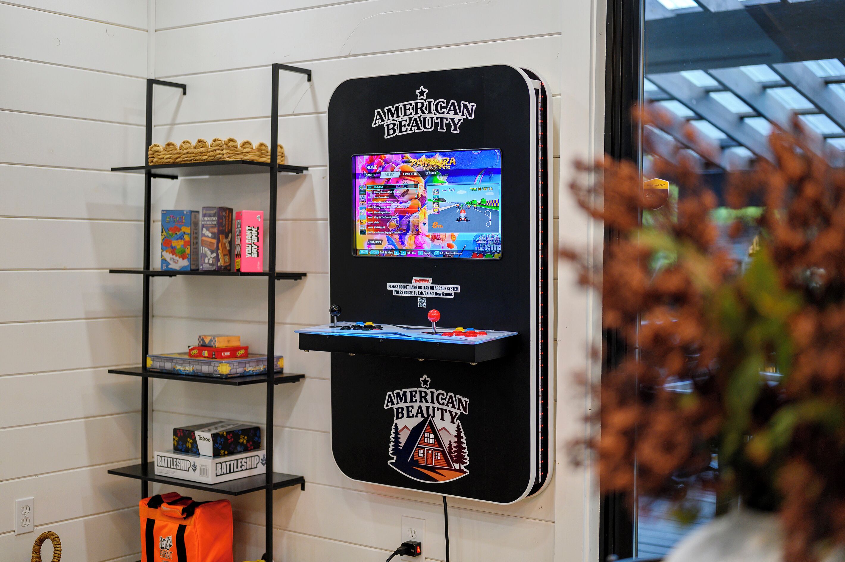 A gaming station with a monitor displaying a racing game, shelves with board games, and a Battleship game box.