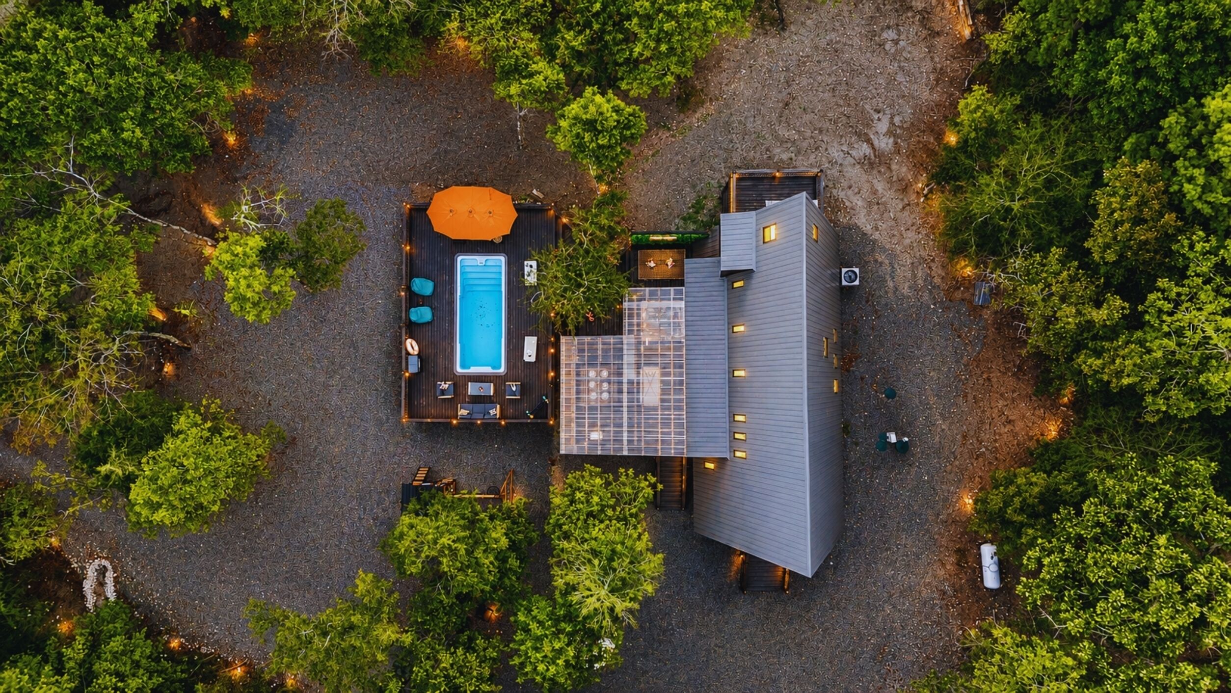 A rooftop pool with a sun lounger and a covered seating area, surrounded by dense greenery.