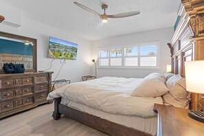 Ein Schlafzimmer mit Bett, Schminktisch und Deckenventilator.