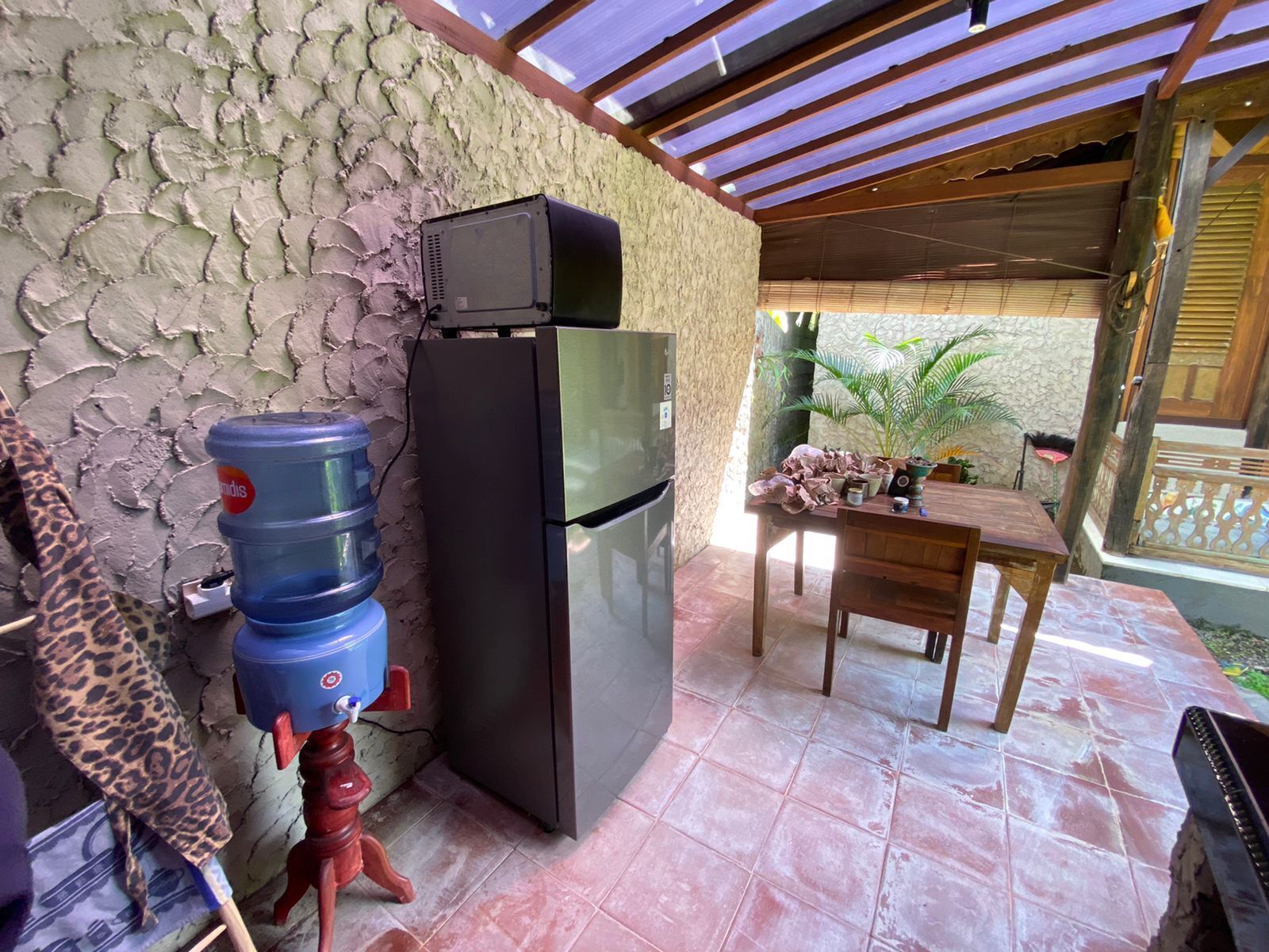Un área de cocina con refrigerador, dispensador de agua y una mesa con sillas.