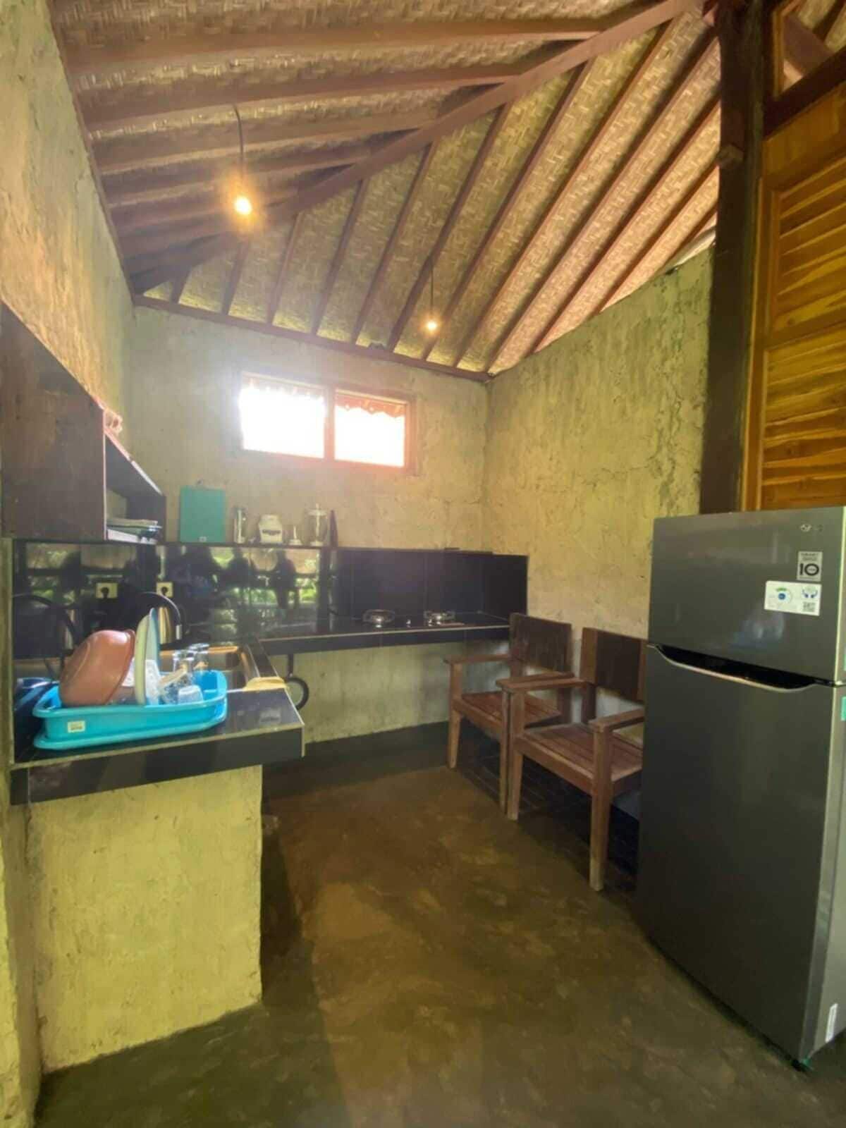 Una cocina compacta con un refrigerador, un lavamanos y una ventana que proporciona luz natural.