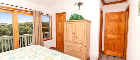 A bedroom with a bed, wooden wardrobe, and a window with curtains.